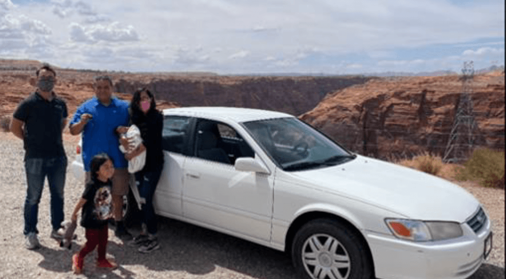 Family posing in front of a white Toyota Camry with a canyon backdrop