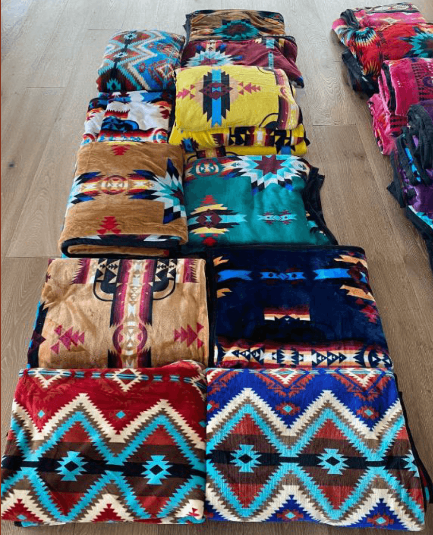 Colorful Navajo-patterned blankets laid out on a hardwood floor